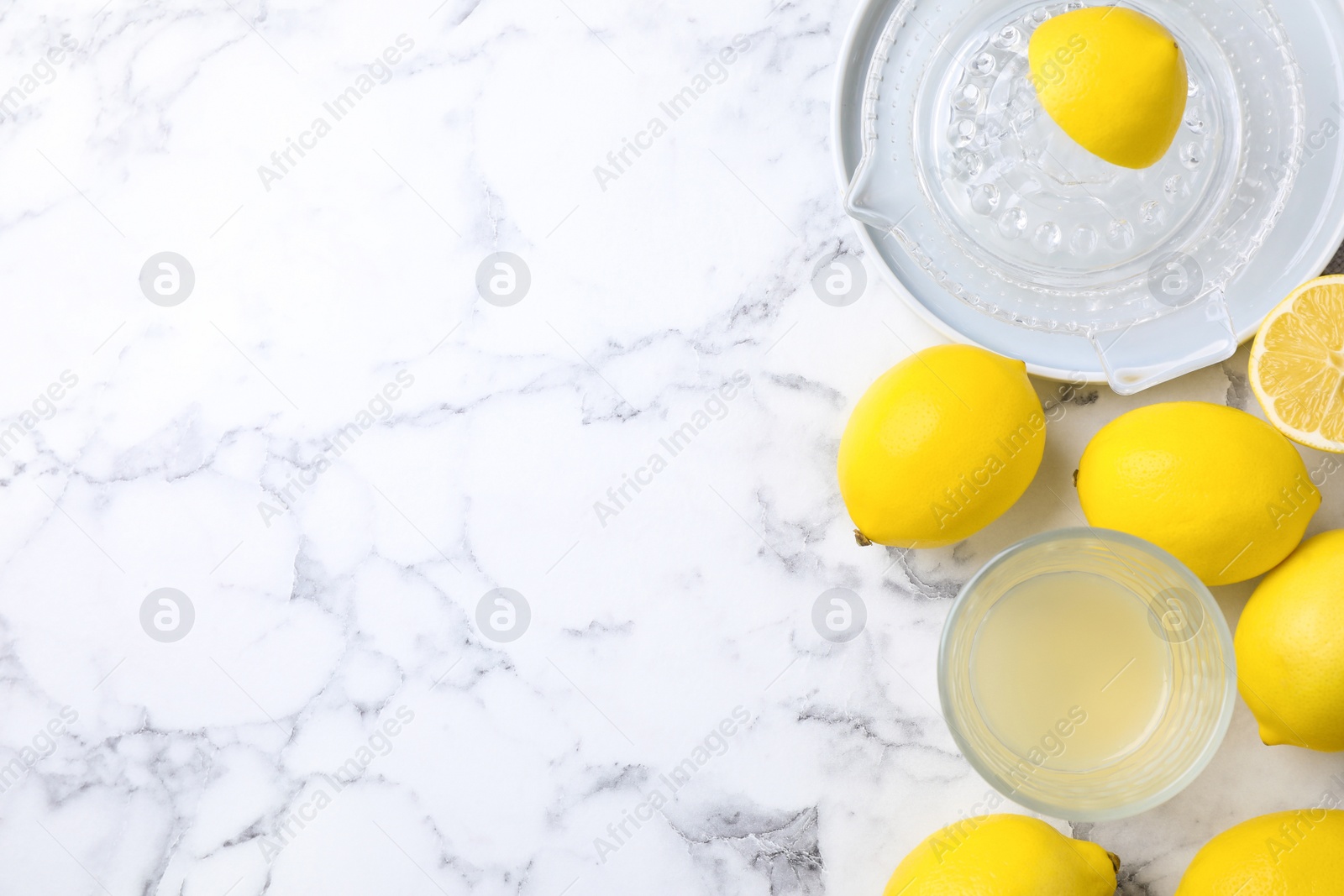 Photo of Flat lay composition with freshly squeezed lemon juice on white marble table. Space for text