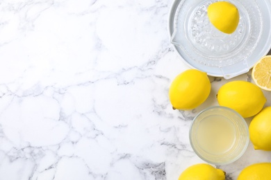 Flat lay composition with freshly squeezed lemon juice on white marble table. Space for text
