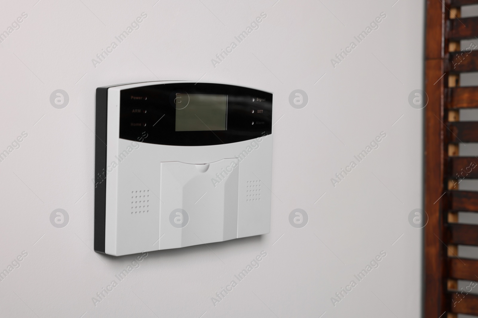 Photo of Home security alarm system on white wall indoors, space for text