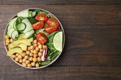 Photo of Tasty salad with chickpeas and vegetables on wooden table, top view. Space for text