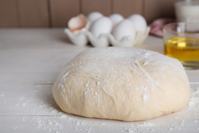 Fresh yeast dough with flour on white wooden table, closeup. Space for text