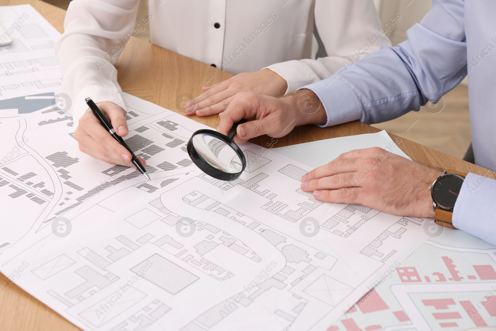 Photo of Professional cartographers working with cadastral map at table, closeup