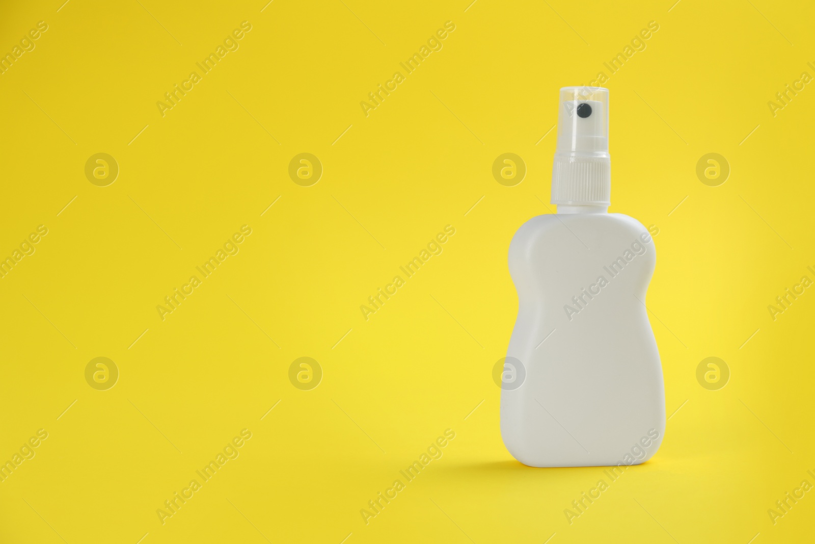 Photo of Bottle with insect repellent spray on yellow background, space for text