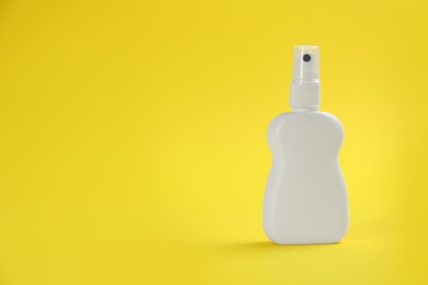 Photo of Bottle with insect repellent spray on yellow background, space for text