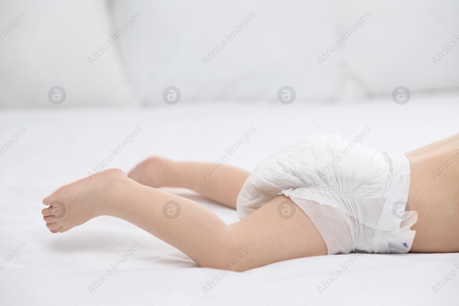 Photo of Cute little baby in diaper on bed, closeup