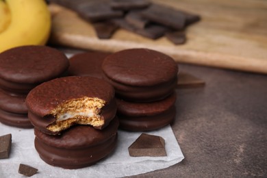 Photo of Tasty banana choco pies and pieces of chocolate on textured table, closeup. Space for text