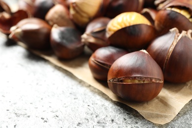 Photo of Delicious roasted edible chestnuts on grey table, closeup