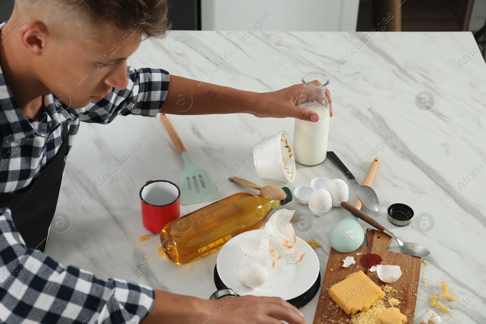 Photo of Man with many dirty dishware, utensils and food leftovers at table in messy kitchen