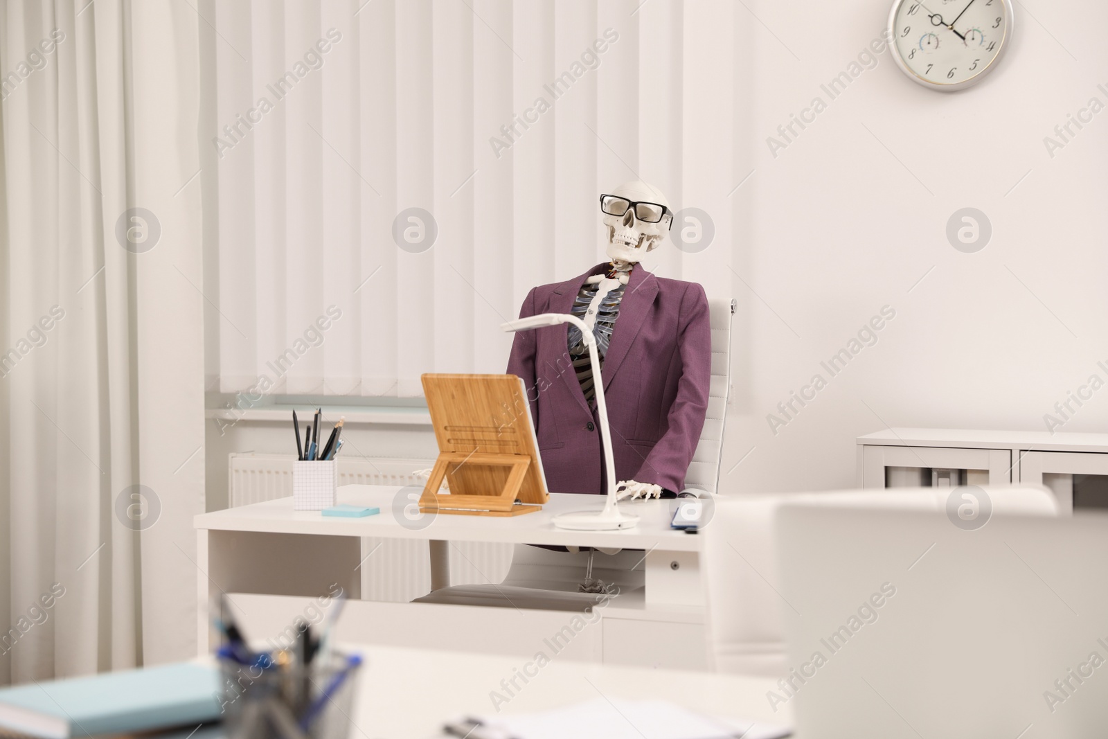 Photo of Human skeleton in suit at table in office