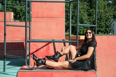 Photo of Woman with kangoo jumping boots sitting in workout park
