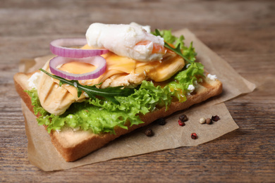 Tasty sandwich with chicken and poached egg on wooden table