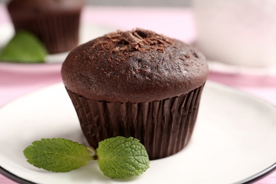 Photo of Delicious chocolate muffin with mint on plate, closeup