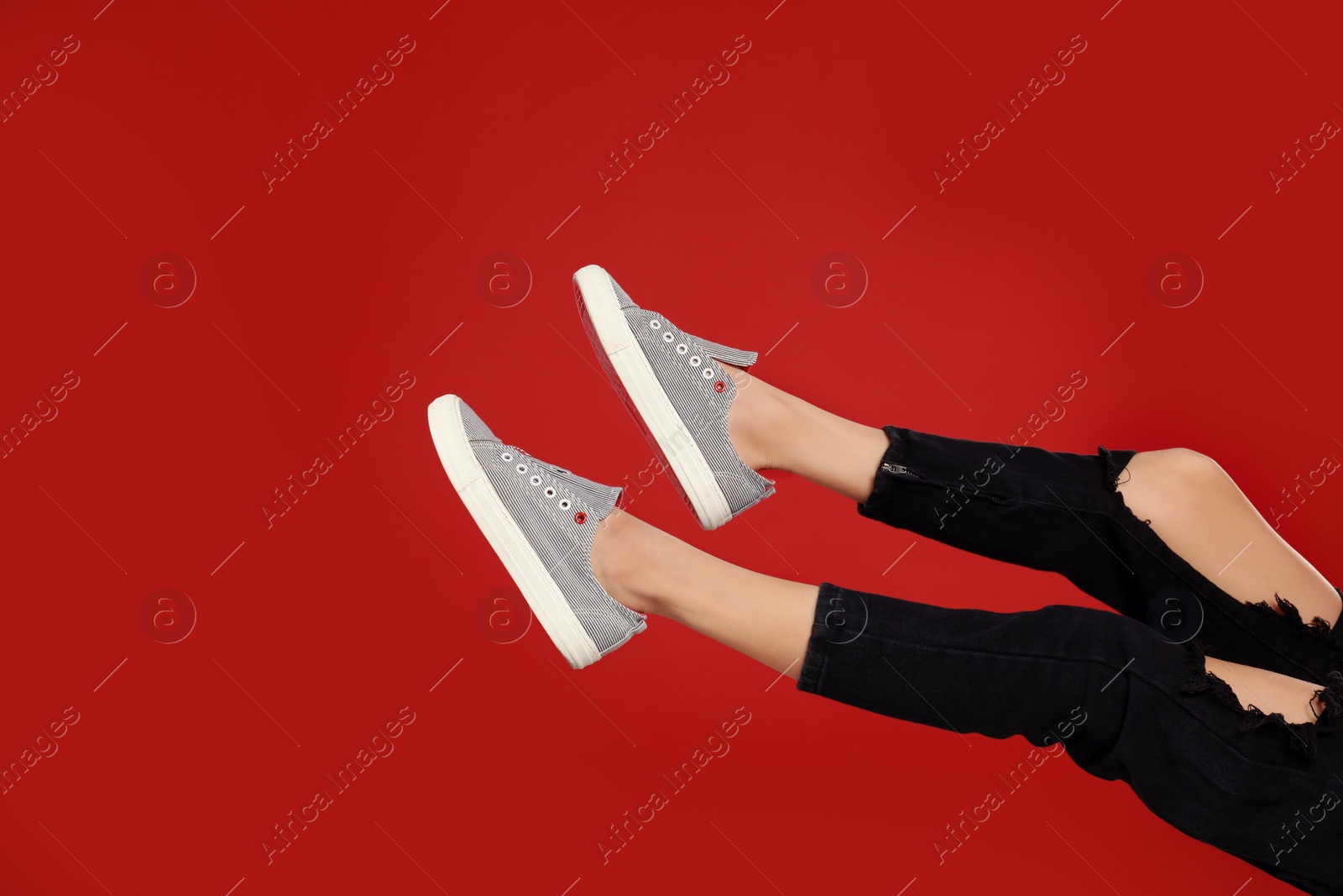 Photo of Woman in stylish sport shoes on red background