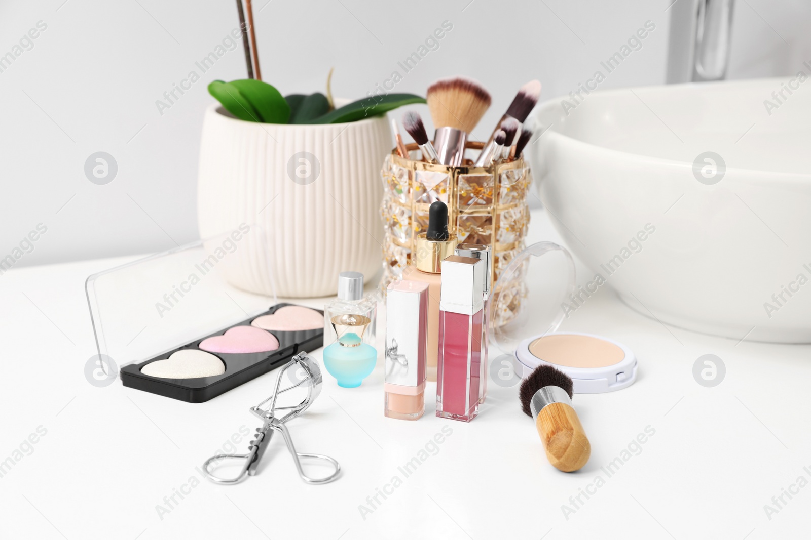 Photo of Different makeup products and houseplant near sink on bathroom counter