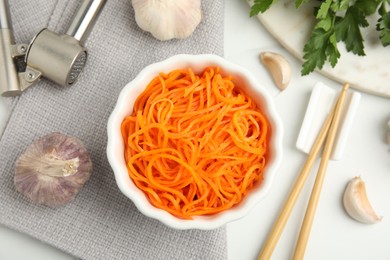 Photo of Delicious Korean carrot salad, garlic and parsley on white table, flat lay