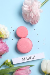 Photo of International Women's day. 8th of March made with delicious macarons and beautiful flowers on light blue background, flat lay