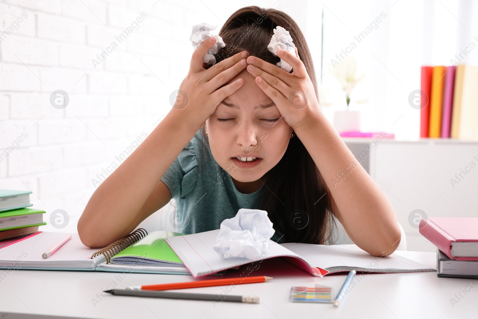 Photo of Emotional preteen girl at table. Doing homework