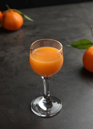 Photo of Delicious tangerine liqueur and fresh fruits on grey table