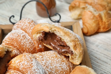 Photo of Tasty croissants with sugar powder and chocolate on tray, closeup