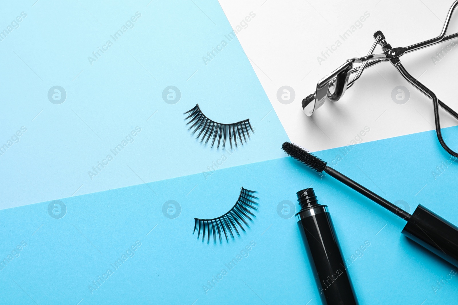 Photo of False eyelashes, curler and mascara on color background, space for text