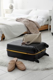 Photo of Suitcase packed for trip, shoes and fashionable accessories on floor in bedroom