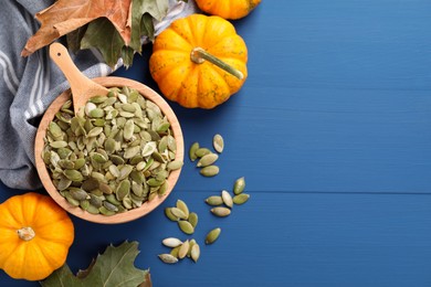 Photo of Bowl with seeds, fresh pumpkins and dry leaves on blue wooden table, flat lay. Space for text