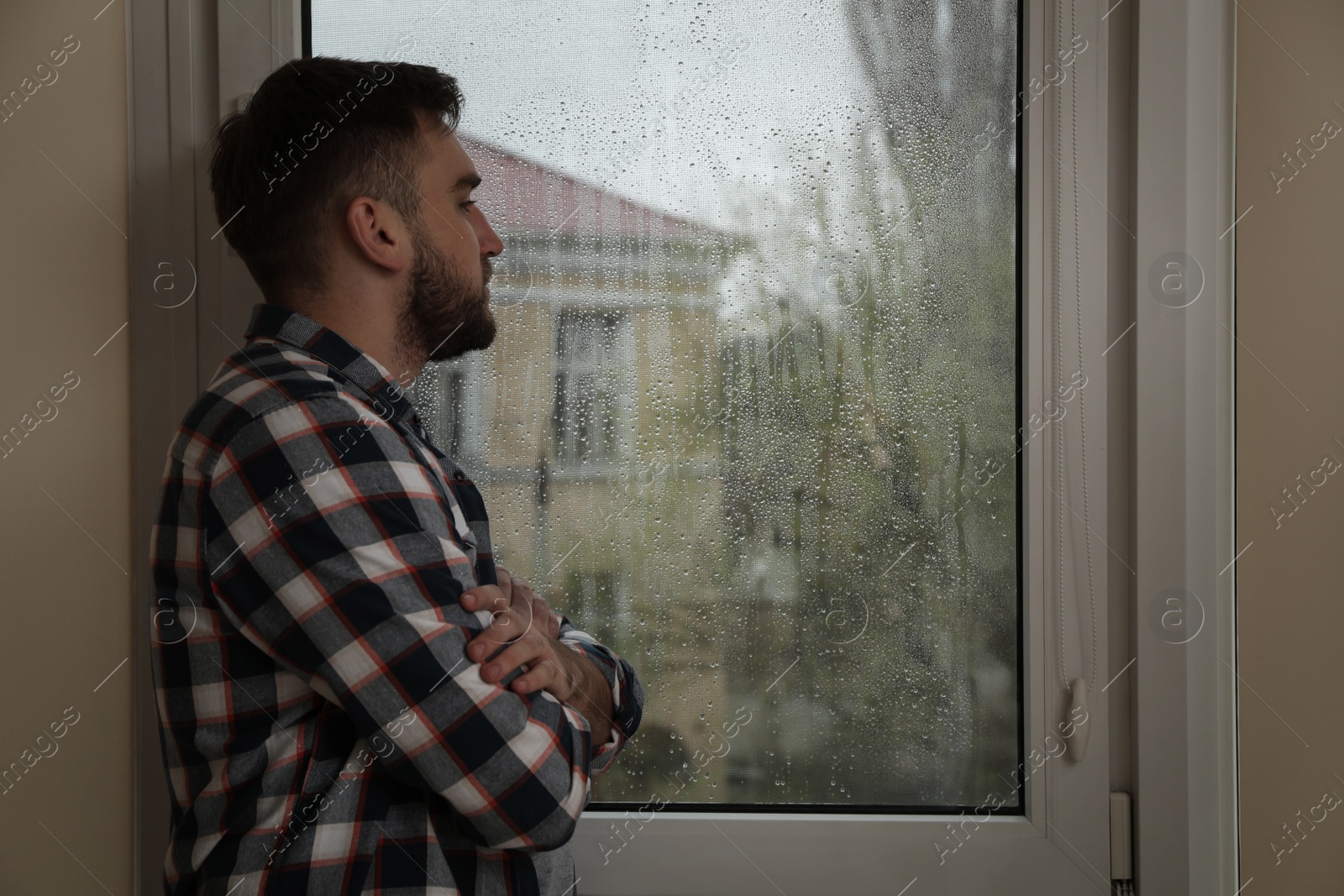 Photo of Depressed man near window at home. Space for text