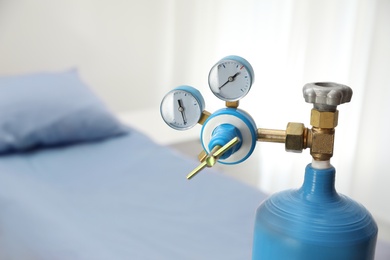 Medical oxygen tank in hospital room, closeup. Space for text