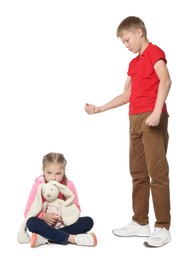 Photo of Boy with clenched fist looking at scared girl on white background. Children's bullying