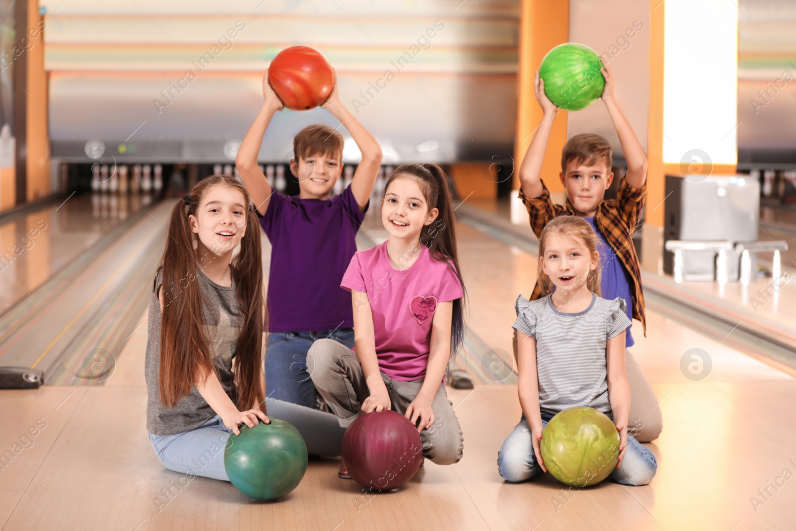 Photo of Happy children with balls in bowling club