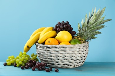 Photo of Wicker bowl with different ripe fruits on turquoise wooden table