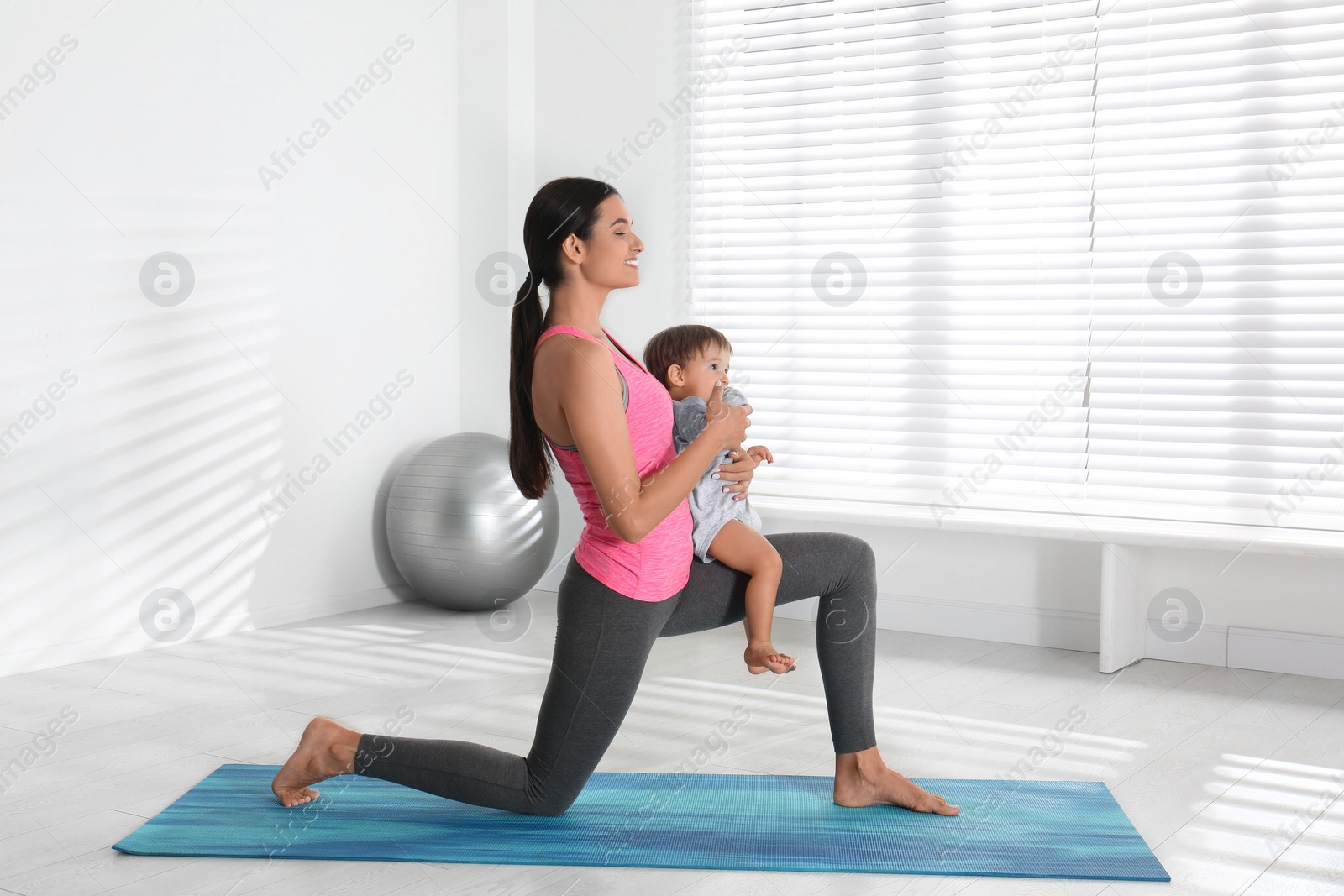 Photo of Young woman doing exercise with her son indoors. Home fitness