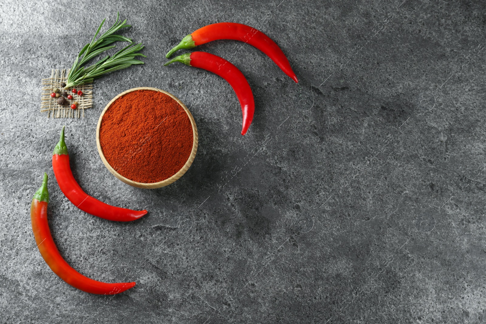 Photo of Bowl of ground red pepper with ingredients on grey table, flat lay. Space for text