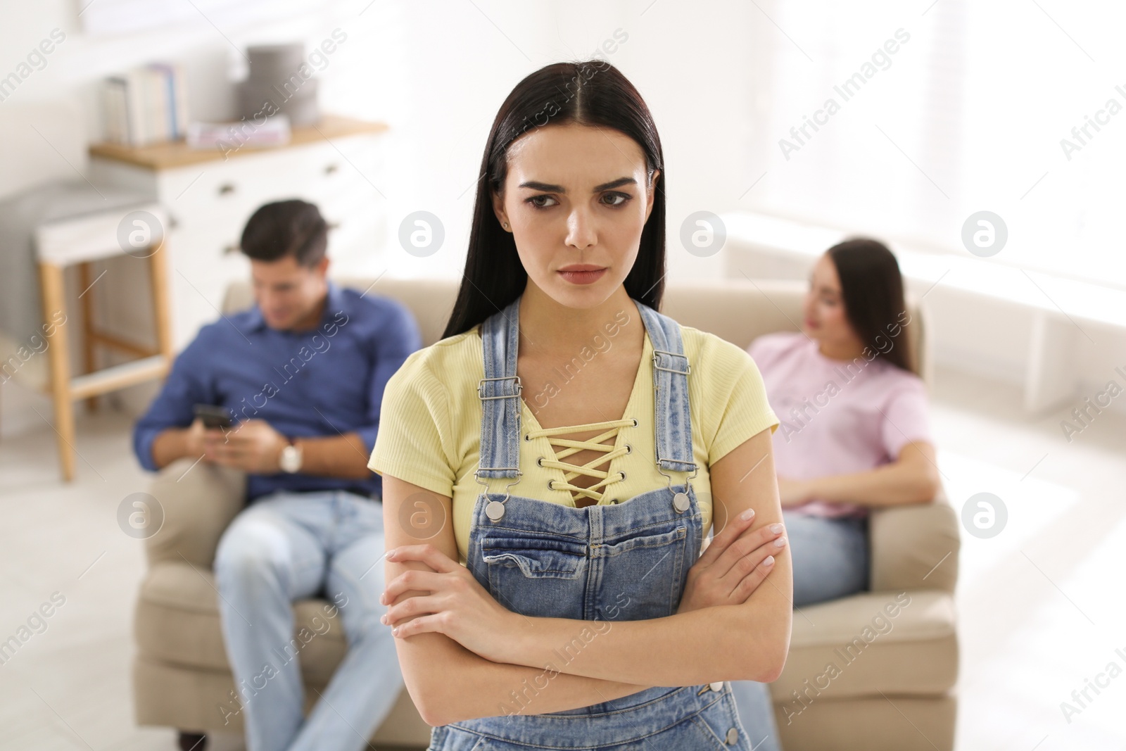 Photo of Unhappy woman feeling jealous while couple spending time together at home