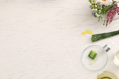 Developing cosmetic oil. Flat lay composition with laboratory glassware and flowers on white wooden table, space for text