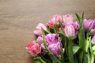 Photo of Beautiful bouquet of colorful tulip flowers on wooden table, flat lay. Space for text