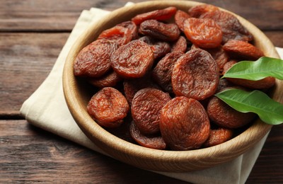 Bowl of tasty apricots on wooden table, closeup. Dried fruits