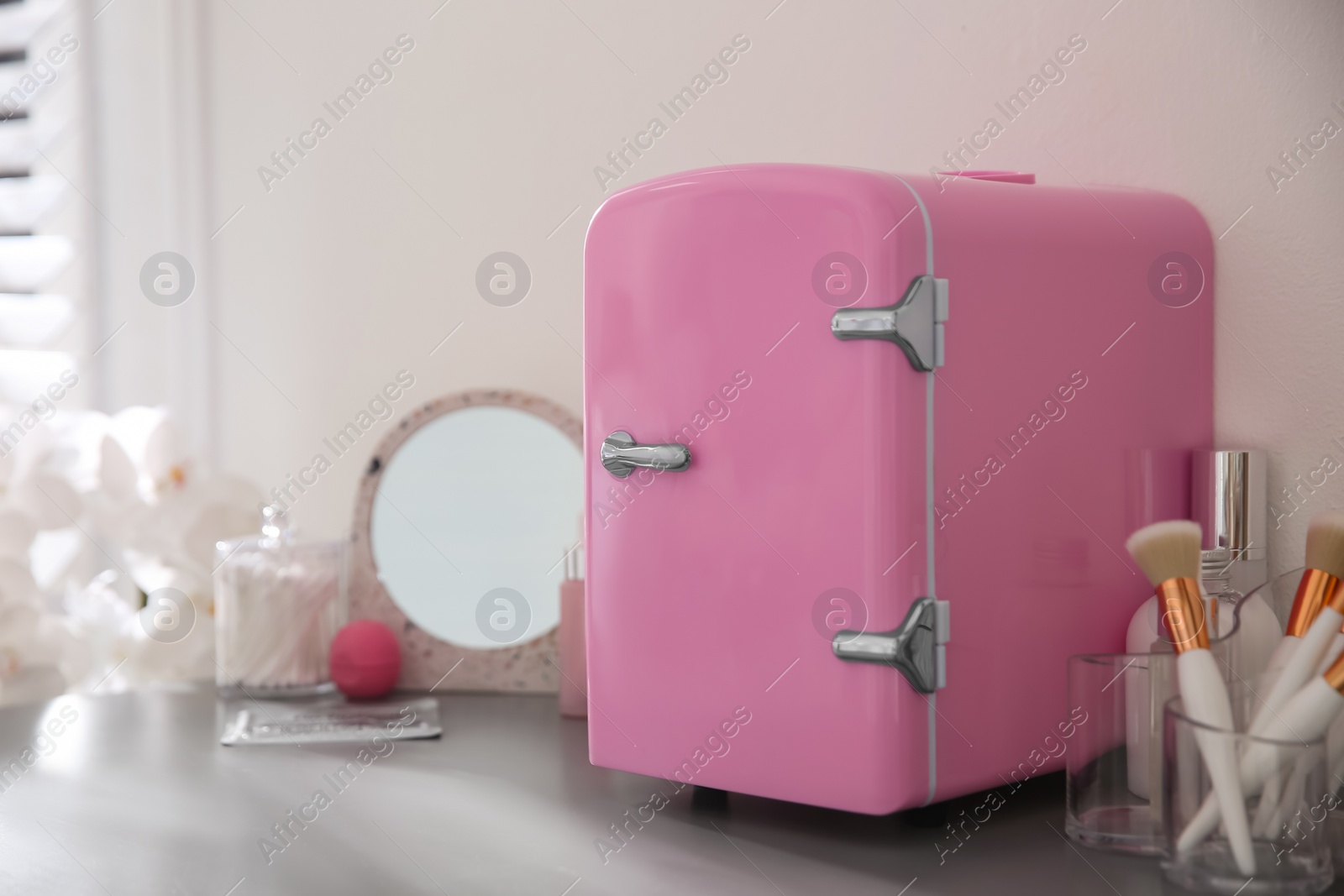 Photo of Cosmetics refrigerator and skin care products on grey vanity table indoors