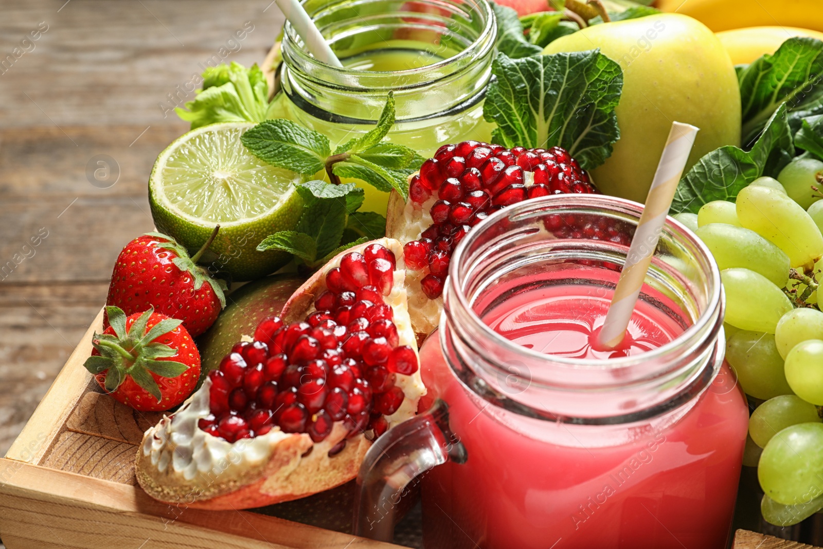 Photo of Mason jars with juices and fresh fruits in wooden crate