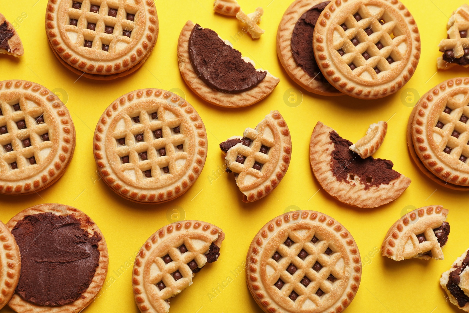 Photo of Tasty sandwich cookies with cream on yellow background, flat lay