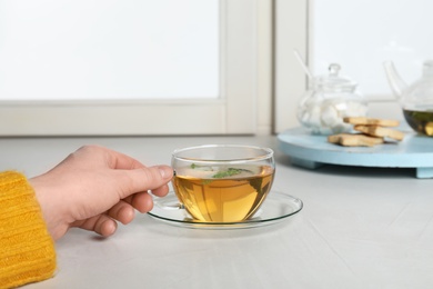 Woman with cup of tea at window, closeup. Winter drink