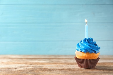 Photo of Delicious birthday cupcake with candle on table