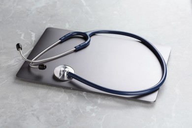 Photo of Modern laptop and stethoscope on grey table