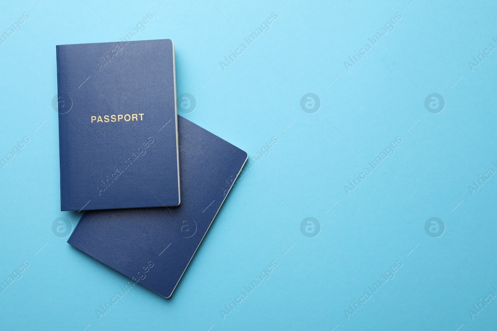 Photo of Blank passports on light blue background, flat lay with space for text