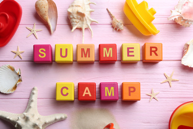 Flat lay composition with phrase SUMMER CAMP made of cubes on pink wooden background