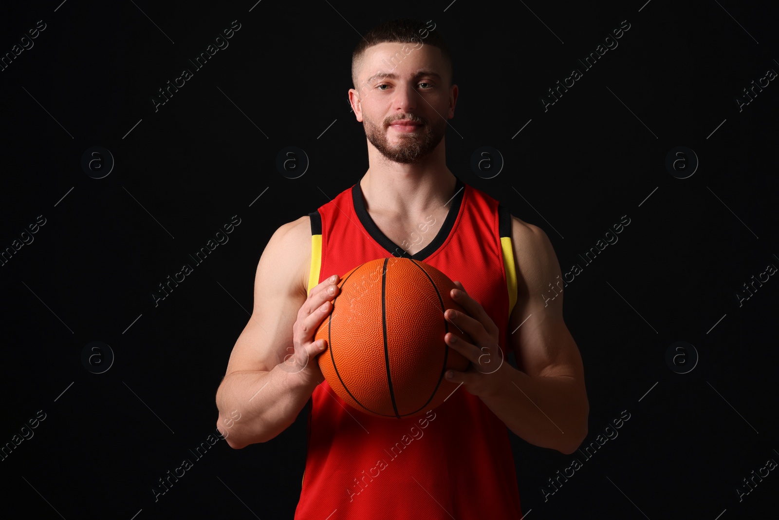 Photo of Athletic young man with basketball ball on black background