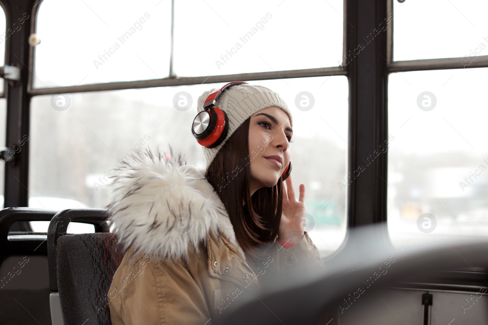 Photo of Young woman listening to music with headphones in public transport