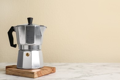 Photo of Moka pot on white marble table. Space for text