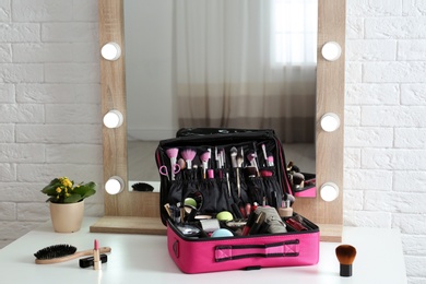 Photo of Beautician case with professional makeup products and tools on dressing table