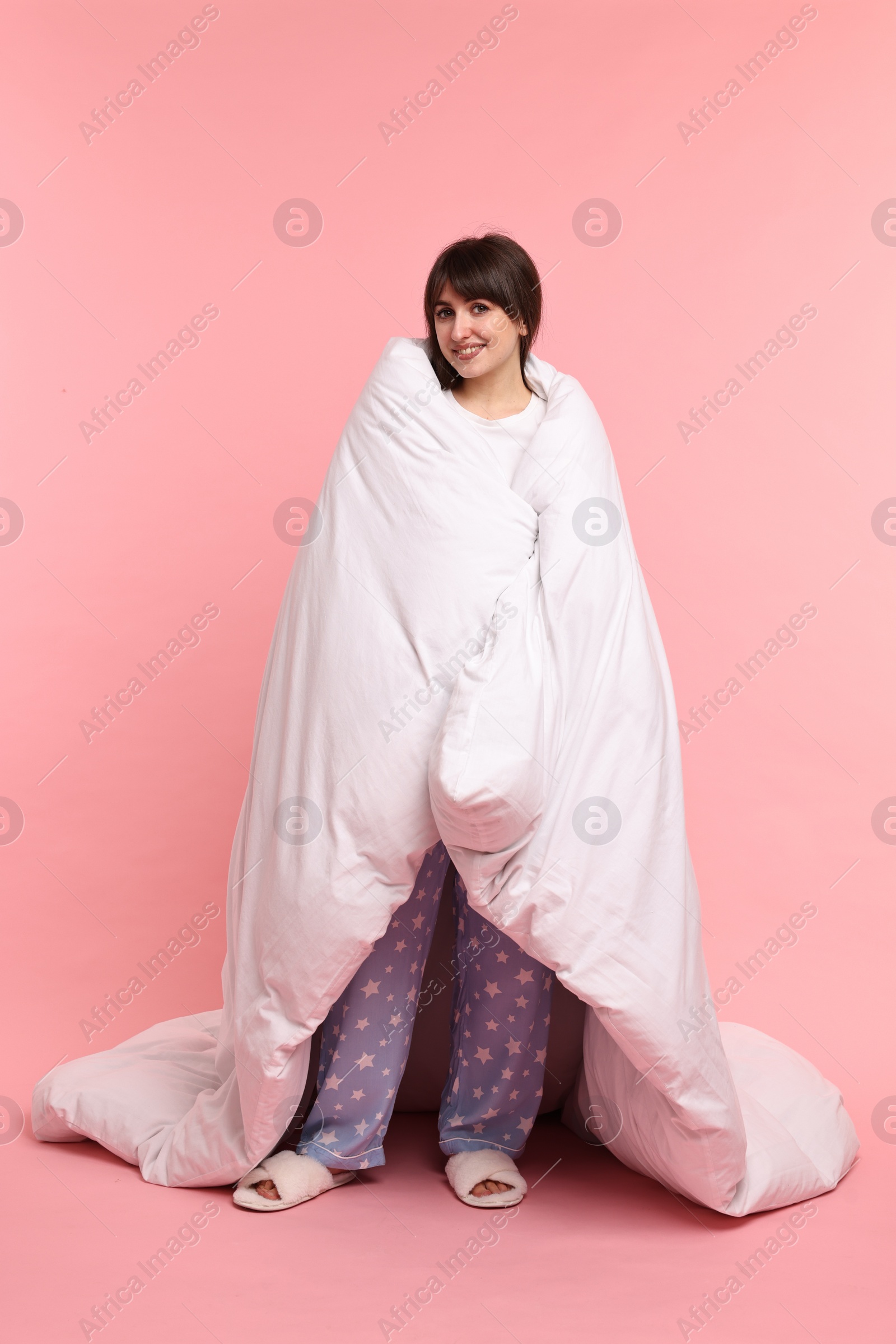 Photo of Happy woman in pyjama wrapped in blanket on pink background